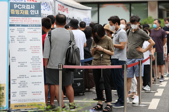 People wait in line to get tested for Covid-19 at a public health center in Gangnam, southern Seoul, on Sunday. [YONHAP]