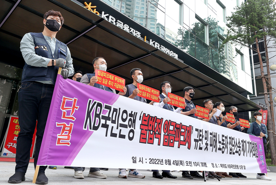 KB Kookmin Bank's labor union holding a protest in front of the bank's headquarters in Yeouido on Thursday, demanding that the bank end its peak-wage system and compensate the pay cut of employees under the program. [YONHAP] 