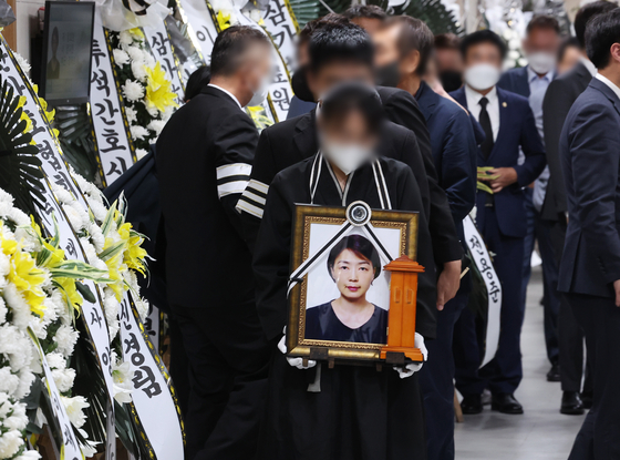 The daughter of Hyeon Eun-kyeong, a 50-year-old nurse who died last Friday in a hospital trying to save patients from a blaze, holds her mother’s portrait at the Gyeonggi Provincial Medical Center Icheon Hospital on Sunday. [YONHAP]