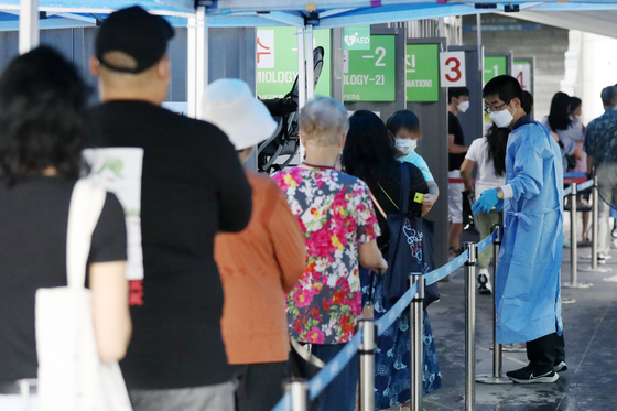 People wait in line to get tested for Covid-19 at a testing center in Yongsan District, central Seoul, Monday. [NEWS1]