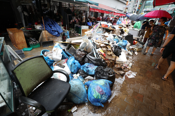 Merchants at Namseong Market in Dongjak District, southern Seoul gather garbage on Tuesday as they clean up after Monday's flooding. Dongjak District suffered some of the heaviest rainfall on Monday. [NEWS1]