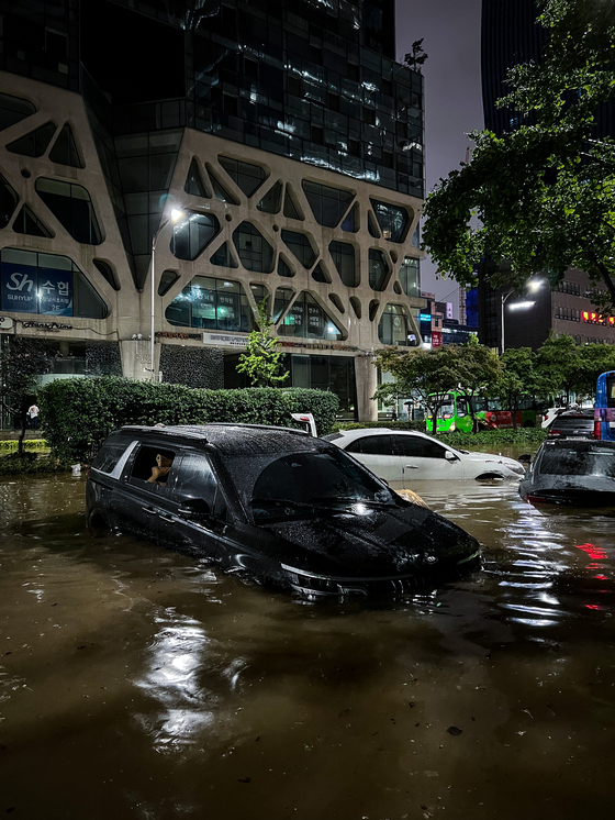 Vehicles lie abandoned on Monday late evening after being submerged by a flash flood near Gangnam Station. [MICHAEL LEE]
