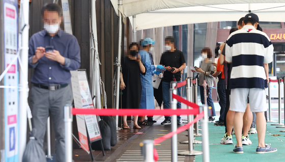 People wait in line to get tested for Covid-19 at a testing center in Songpa District, southern Seoul, Tuesday. [YONHAP]