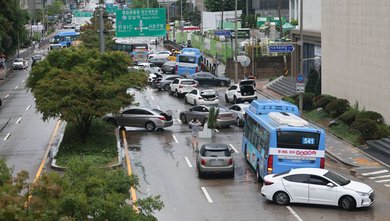  Cars abandoned by their drivers due to heavy rain the previous night are strewn across a road in Seocho-dong, Gangnam, on Tuesday. [YONHAP] 