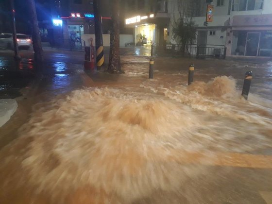A manhole cover is thrown open with water and sewage flows out into the road. [SCREEN CAPTURE]