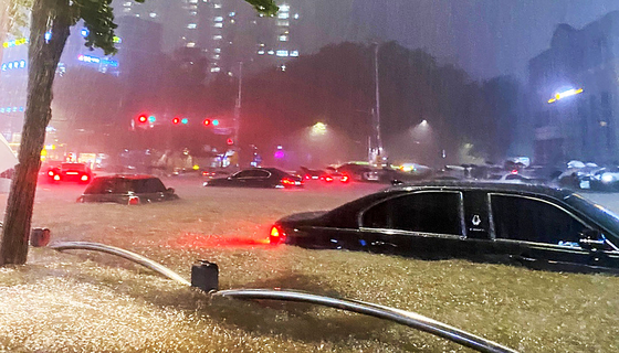 A road near Daechi Station in Gangnam District is flooded due to heavy rain Monday evening. [YONHAP]