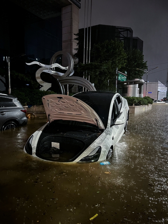 An abandoned Tesla half submerged in Seocho-dong, Gangnam, on Monday. [MICHAEL LEE] 