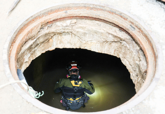 A firefighter searches inside a sewer in Seocho District for missing people Wednesday afternoon, after heavy rains flooded much of southern area of Seoul Monday evening. [WOO SANG-JO]