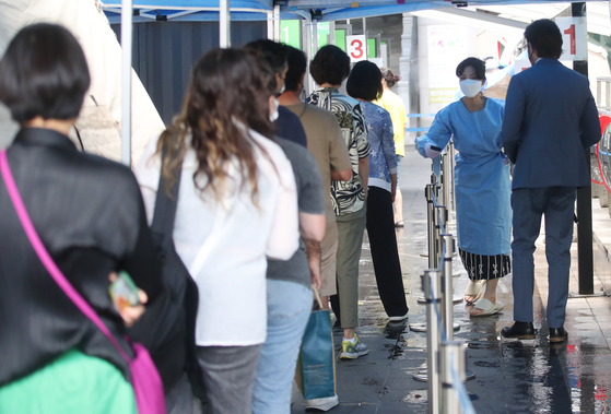 People wait in line to get tested for Covid-19 at a testing center in Yongsan District, central Seoul, Wednesday. [NEWS1]