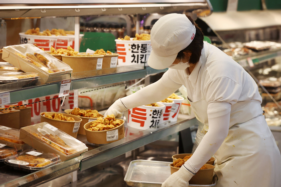 An employee displays a container of fried chicken at a discount mart in Seoul on Wednesday. Fried chicken sold at discounted prices at supermarket chains, including Homeplus and Emart, is becoming increasingly popular among customers. Lotte Mart started selling fried chicken at a 44 percent discounted price on Wednesday. [YONHAP]