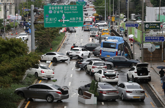 Cars are left abandoned in Seocho District, southern Seoul, on Tuesday after heavy rain on Monday. [NEWS1] 