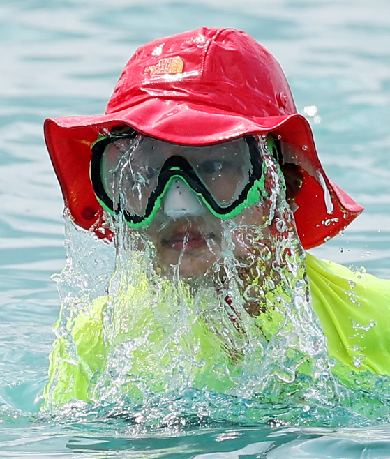 A child wearing a snorkel, swimming hat and rash guard swims in the Nanji Hangang Park swimming pool on Aug. 5, 2022. [YONHAP]