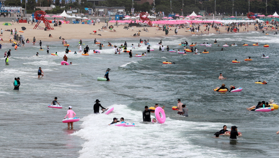 People vacation in Haeundae beach in Busan on Aug. 9, 2022. Note that most are wearing rash guards. [YONHAP]