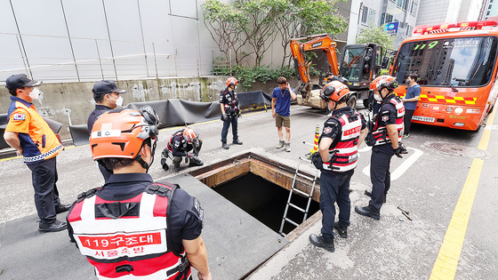 Firefighters search on Wednesday for missing people inside a sewage system in Seocho District, southern Seoul, after record heavy rains hit the central regions of the Korean Peninsula Monday evening. [WOO SANG-JO]