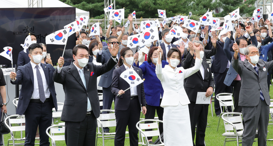 President Yoon Suk-yeol, left, and first lady Kim Keon-hee wave Korean flags during a ceremony marking the 77th Liberation Day on the front lawn of the presidential office in Yongsan District, central Seoul, on Monday. [JOINT PRESS CORPS]