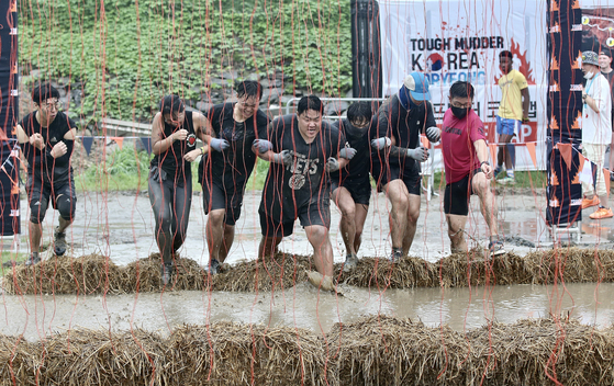 Visitors to the Boryeong Mud Festival in South Chungcheong try a "Tough Mudder" obstacle course on Saturday. [NEWS1]