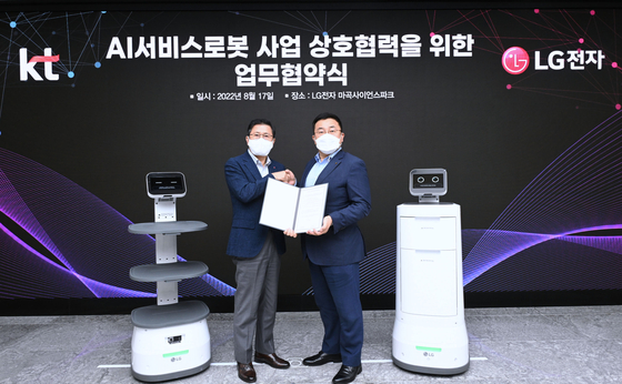 Jang Ik-hwan, left, LG Electronics' executive vice president, and Song Jae-ho, KT’s vice president, pose for a photo during a signing ceremony held at LG Science Park in Gangseo District, western Seoul, on Wednesday. [LG ELECTRONICS]