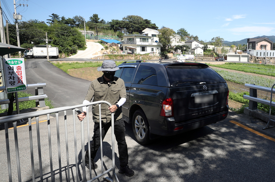 A guard on Sunday afternoon allows a vehicle to pass the security perimeter surrounding Pyeongsan Village in Yangsan, South Gyeongsang, where former President Moon Jae-in's retirement home is located. [YONHAP]