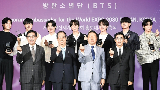 BTS members pose in front of cameras after being appointed as ambassadors for Busan’s bid to host the 2030 World Expo on July 18 at their agency HYBE in Yongsan District, central Seoul. [NEWS1]