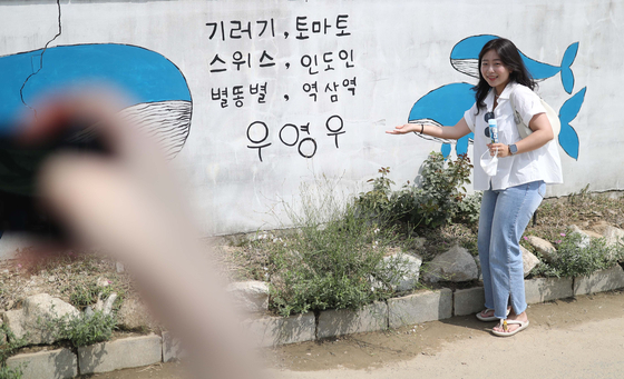 Visitors pose next to a mural of whales, Young-woo's favorite animal, and the catchphrase she always says when introducing herself on July 26, 2022. [YONHAP]