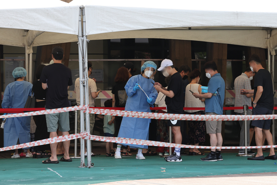 People wait in line at a Covid-19 testing site in Songpa District, southern Seoul on Sunday. [YONHAP] 
