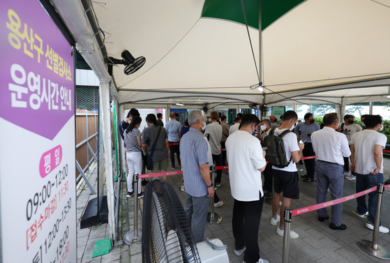 People wait in line at a Covid-19 testing site in Yongsan District, central Seoul, on Monday. [YONHAP]