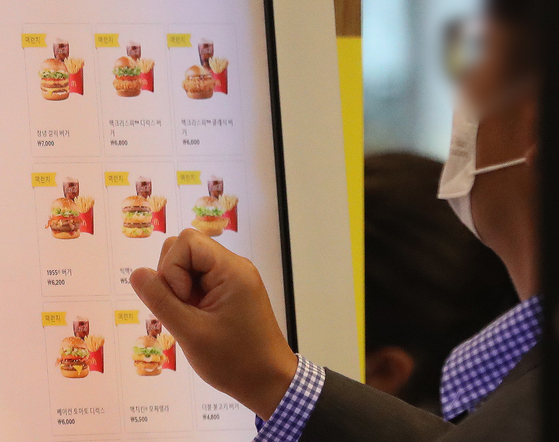 A customer selects menu items from a kiosk at a McDonald's in downtown Seoul on Wednesday. McDonald's Korea will raise its prices by an average of 4.8 percent starting Thursday, in a second price hike this year after the fast food chain raised prices by an average of 100 to 300 won (7 to 22 cents) in February. Burger franchises are not the only ones upping costs — chicken and pizza franchises and coffee chains have also increased their prices in recent weeks. [NEWS1]