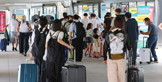 Travelers wait in front of a Covid-19 testing center at Incheon International Airport on Wednesday. [YONHAP]