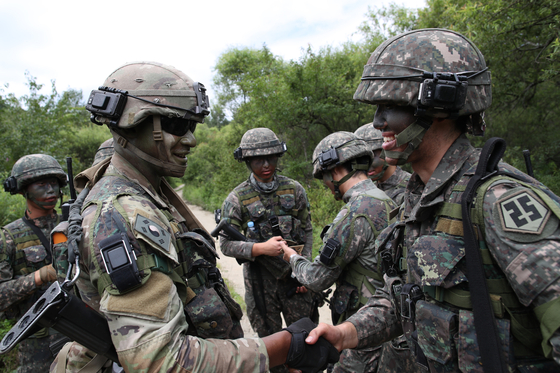 Korean and American soldiers shake hands during a joint drill at the Korea Combat Training Center in Inje, Gangwon, on Wednesday. [YONHAP]