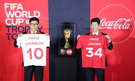 Korean football legends Cha Bum-kun, left, and Park Ji-sung pose with the World Cup trophy at The Hyundai Seoul in Yeouido, western Seoul on Wednesday. [NEWS1]