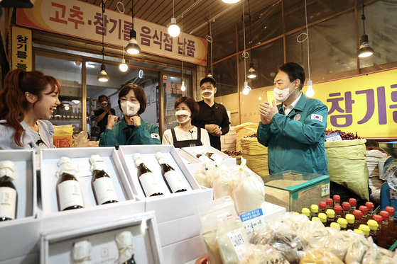 President Yoon Suk-yeol, right, takes part in a sesame oil vendor’s live commerce broadcast during a visit to the Amsa Complex Market, a traditional market in Gangdong District, eastern Seoul, Thursday. [PRESIDENTIAL OFFICE]