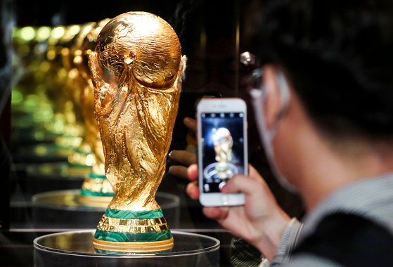 A visitor photographs the World Cup trophy at The Hyundai Seoul in Yeouido, western Seoul. The trophy stopped in Korea to kick off the second leg of its world tour ahead of the 2022 Qatar World Cup in November. [NEWS1]