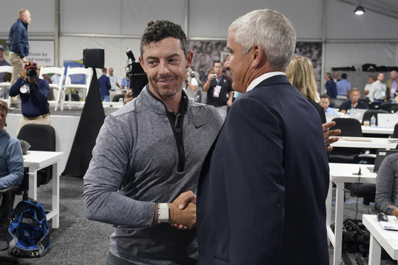 Rory McIlroy, of Northern Ireland, left, shakes hands with PGA Tour Commissioner Jay Monahan after a press conference at East Lake Golf Club prior to the start of the Tour Championship golf tournament on Wednesday in Atlanta, Georgia. [AP/YONHAP]