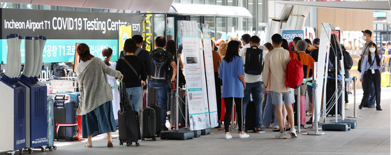 People wait in line to get tested for Covid-19 at Terminal 1 of the Incheon International Airport on Sunday. [YONHAP] 