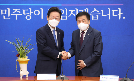 Lee Jae-myung, left, new chairman of the Democratic Party, receives a congratulatory orchid from President Yoon Suk-yeol via Lee Jin-bok, senior presidential secretary for political affairs, at the National Assembly in Yeouido, western Seoul, Tuesday. [JOINT PRESS CORPS]