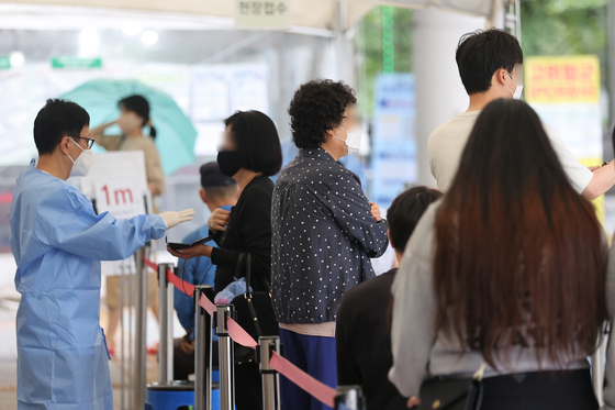 People wait in line to get tested for Covid-19 in Mapo District, western Seoul on Tuesday. [YONHAP]