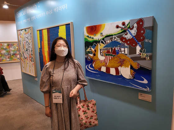 Jung pose in front of her work ″Poolside Party″ on Wednesday at the Blue House's Chunchugwan, where the exhibit kicked off. [YIM SEUNG-HYE]