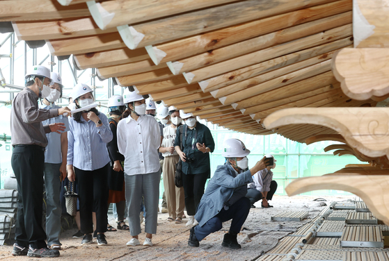 A group of visitors get a glimpse of a part of Gyeongbok Palace that is being restored. The people applied for the special tour in advance.  [YONHAP]