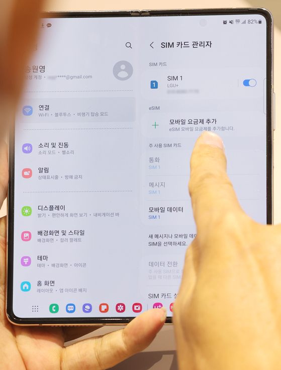 A customer adjusts the settings on their phone after installing an eSIM at the LG U+ Namdaemun branch in central Seoul on Thursday. The eSIM function, which allows two numbers to be used simultaneously on one phone, launched the same day. [YONHAP]