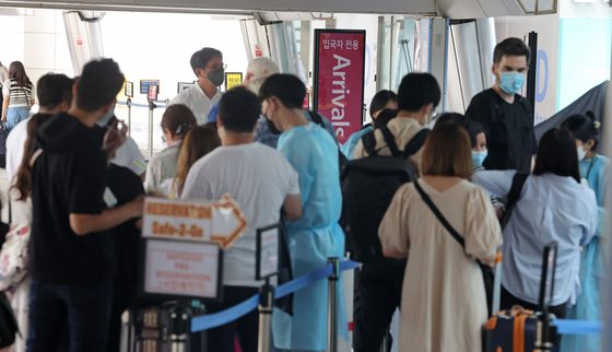 People stand in line to get tested for Covid-19 at Terminal 1 of the Incheon International Airport on Wednesday. [YONHAP]