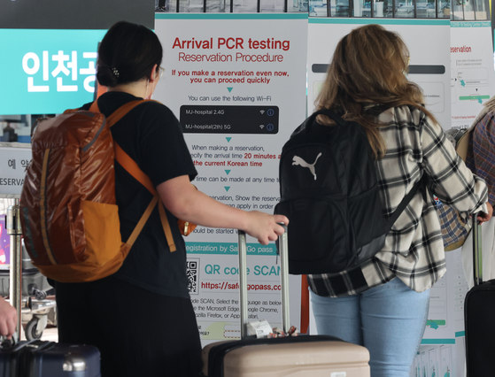 Incoming travelers wait in line to get tested for Covid-19 at Terminal 1 of Incheon International Airport on Thursday. [YONHAP]