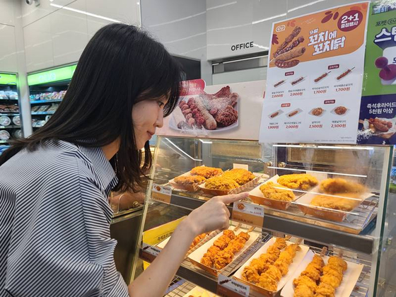 A customer checks out a display of fried chicken pieces at a CU store. [CU]