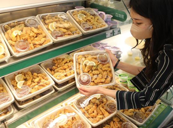 A customer examines a bucket of tangsuyuk, or sweet and sour pork, at the deli corner at Lotte Mart's Seoul Station branch on Wednesday. [LOTTE MART]