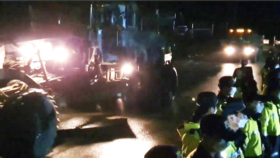 In this photo taken by a local civic group, vehicles and equipment enter the Terminal High Altitude Area Defense (Thaad) base in Seongju, North Gyeongsang under heavy police protection early Sunday. [YONHAP]