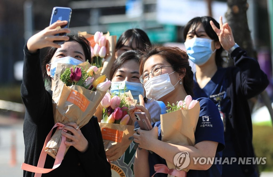 Nurses at a hospital in Jungnang District, central Seoul, pose with bouquets of tulips gifted from the Netherlands Embassy in Seoul on April 8, 2020. [YONHAP]