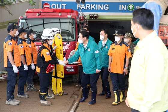 President Yoon Suk-yeol, center, thanks firefighters Wednesday for their efforts to rescue people from a flooded underground parking lot at an apartment complex in Nam District in Pohang, North Gyeongsang, after Typhoon Hinnamnor passed earlier this week. [JOINT PRESS CORPS]