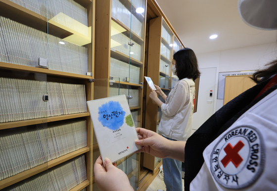 Employees at the Red Cross committee headquarters in Jung District, central Seoul hold video messages recorded by South Koreans for their North Korean relatives on Thursday. [YONHAP]