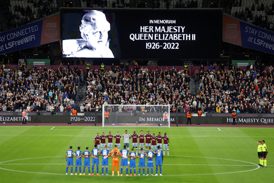 Players and fans from West Ham and Romanian side FCSB stand to honor Britain's Queen Elizabeth II following her death on Thursday before a Europa Conference League match in London. [REUTERS/YONHAP]