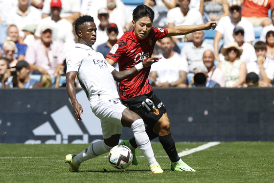 RCD Mallorca midfielder Lee Kang-in, right, fights for the ball against Real Madrid's Brazilian striker Vinicius Jr during their LaLiga soccer match between Real Madrid and RCD Mallorca at Bernabeu stadium in Madrid, Spain, on Sunday. [EPA/YONHAP]