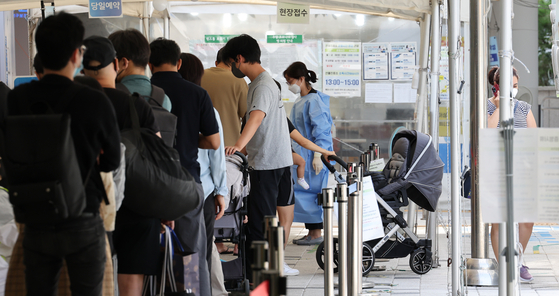 People wait in line to get tested for Covid-19 in front of a center in Mapo District, western Seoul on Thursday. [YONHAP]